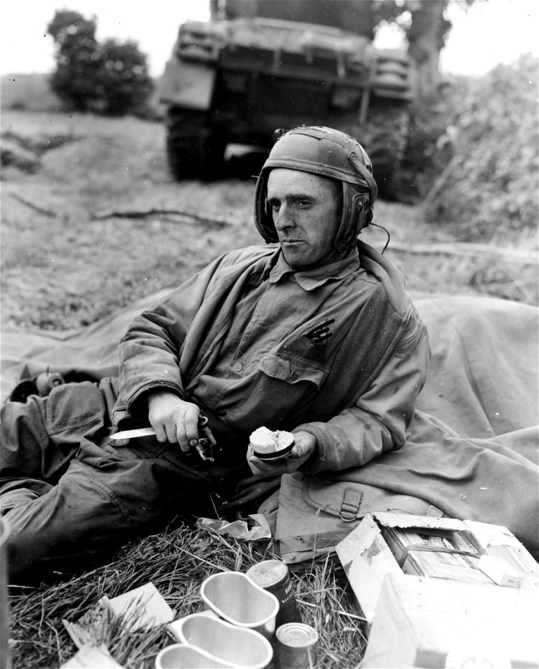 SC 396845 - Pfc. Jerry C. Coleman, of Los Angeles, Cal., assistant driver of a tank attached to an armored unit serving somewhere in France, takes time out during a lull in the action to eat his "K" rations.