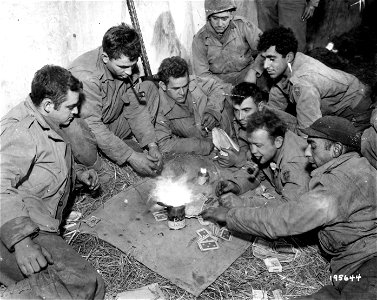 SC 195644 - A can of gasoline provides illumination for this card game by members of the 79th Infantry Division, somewhere in France. 17 October, 1944. photo