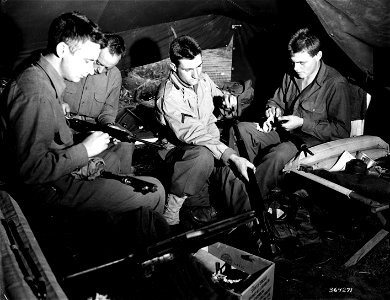 SC 364271 - Four infantrymen awaiting orders for the big push against the European continent, use their spare time in keeping their rifles in perfect condition. photo