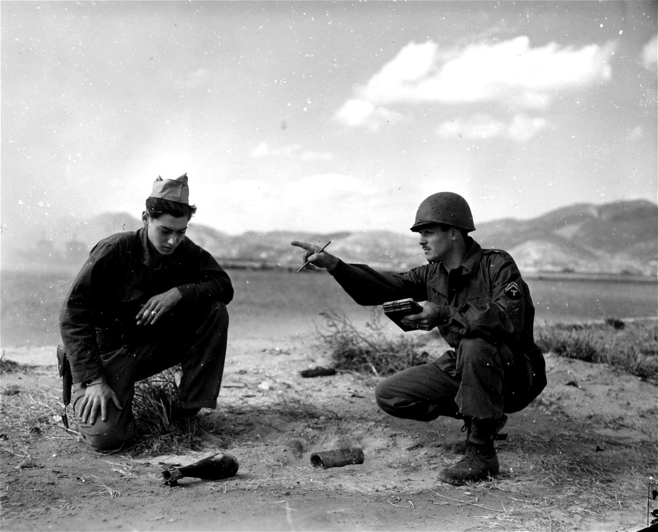 SC 221611 - Two soldiers examine shells which landed ashore from ammunition barge which caught fire and exploded at time of ASCOM QM warehouses fire. Fusan, Korea, 28 October, 1945.