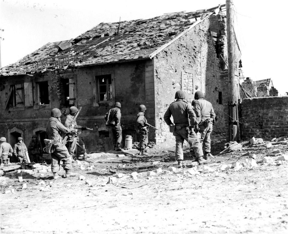 SC 270629 - 7th U.S. Army infantrymen of the 7th Inf. Regt. prepare to rush house in which Nazi snipers are hidden. Guiderkirch, France. 15 March, 1945.