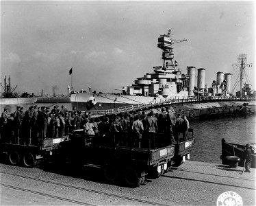 SC 364346 - A group of soldiers on tour of the port area pass the cruiser Memphis, flagship of Admiral Hewitt, anchored beside a sunken ship used as a pier.