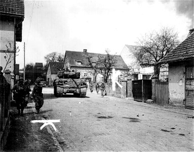 SC 335305 - Armored column takes German town. Here, tank-supported infantry on left get instructions from officer on cleaning the enemy out of houses.