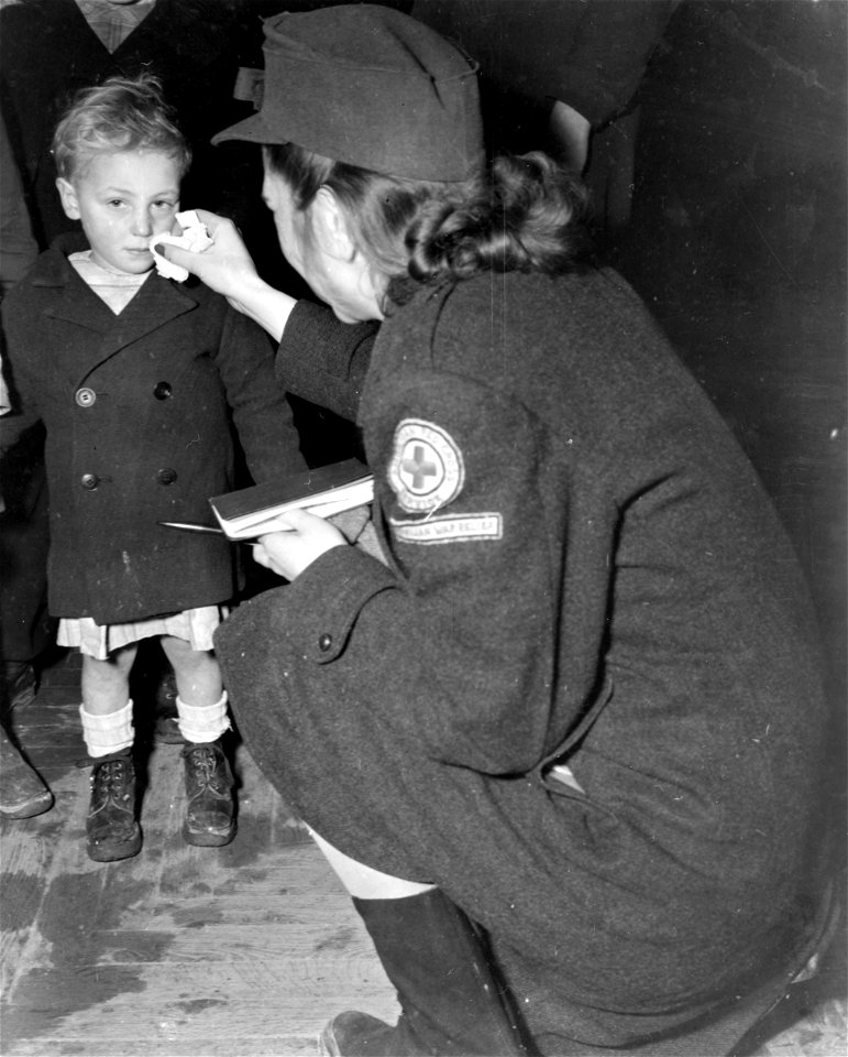 SC 329790 - Nancy Hohgland, Orange, Va., American Red Cross worker, wipes face of French child waiting for issue of clothing in Nantes, France.