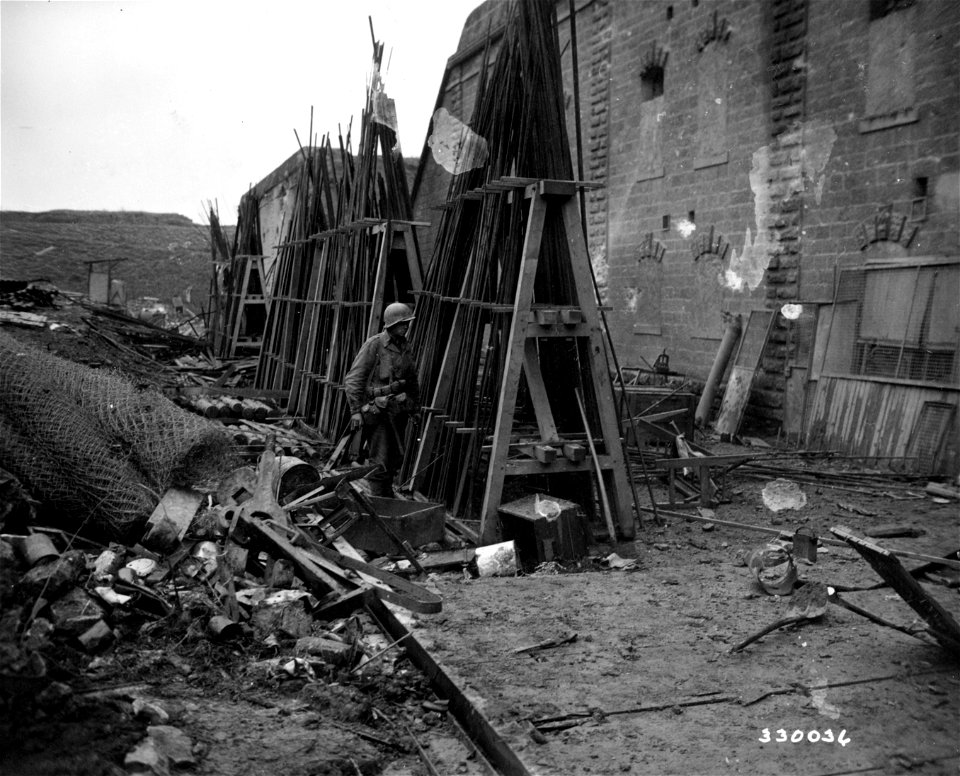 SC 330036 - Sgt. Willis E. Young of Hollcut(?), Massachusetts, looks over a German stockpile of metal. The Germans used this metal to make their own shells near Metz, France, at Fort Jeanne D'Arc. 16 December, 1944.