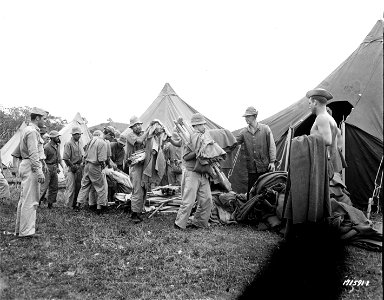 SC 171591-R - First Island Command, New Caledonia. Jap prisoners receive their cot, mosquito netting and three blankets at new prison camp where they will live in tents after having been housed temporarily in a warehouse. 7 January, 1943. photo