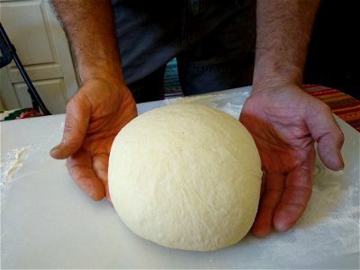 Man's hands shaping sourdough into round loaf photo