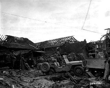 SC 329792 - XIII Corps troops of the 9th U.S. Army line up for coffee and doughnuts at an American Red Cross clubmobile among the ruins of Wurm, Germany. 14 February, 1945. photo