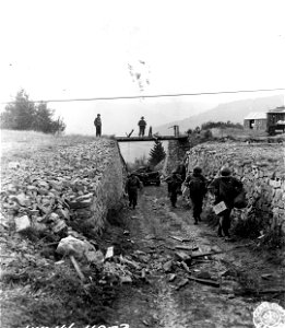 SC 270627 - Men of 15th Inf., 3rd Div., walk up road through the Cleurie Quarry. 6 October, 1944.