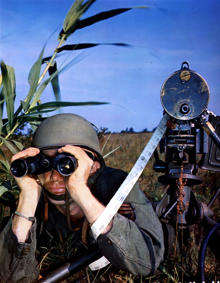 C-3271 - T/Sgt. John Carter, Waltersboro, South Carolina, uses 6x30 Westinghouse binoculars to observe enemy activities for range on his .30 caliber machine gun. May, 1945.
