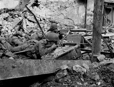SC 364294 - .30 Cal. machine gunner and infantryman with carbine cover street inside Coblenz, Germany.