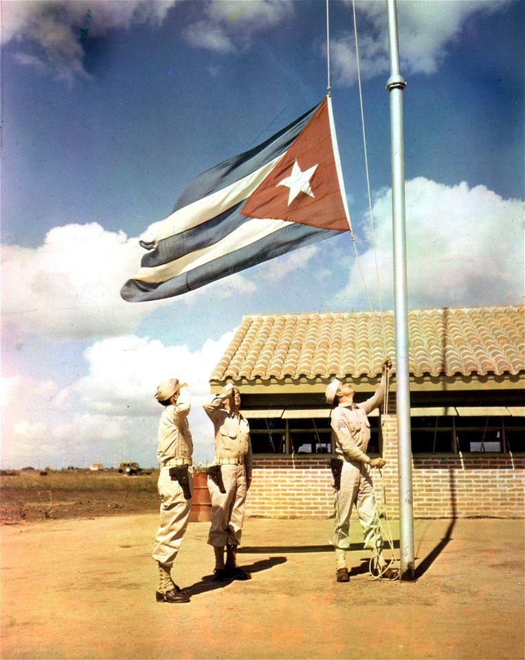 C-926 - While one American soldier raises a Cuban flag, two soldiers stand at attention and salute. Cuba.