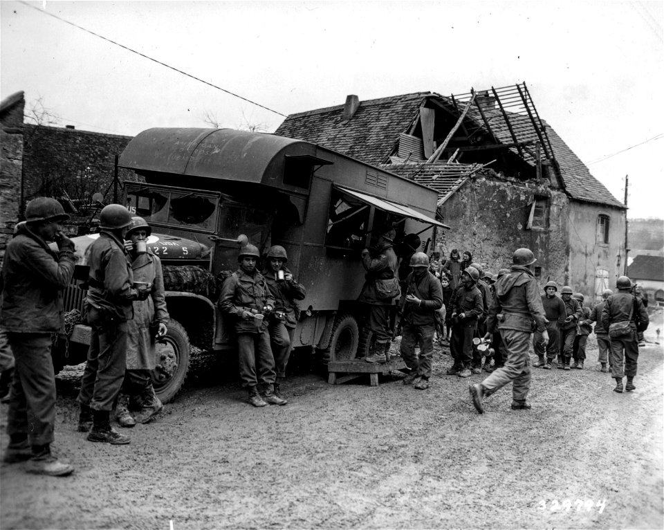 SC 329794 - Soldiers with their mess cups line up at the American Red Cross clubmobile for coffee and doughnuts at the 71st Infantry Regiment, 44th Division, XV Corps, 7th Army front. Achen area, France.