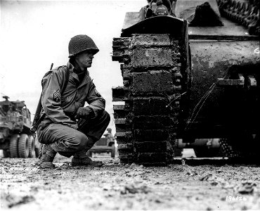 SC 196126 - Sgt. Allan Raines, of 45-56-49th St., Woodside, N.Y., inspects new "Duck Bills" welded on tank treads to give them better traction in mud.