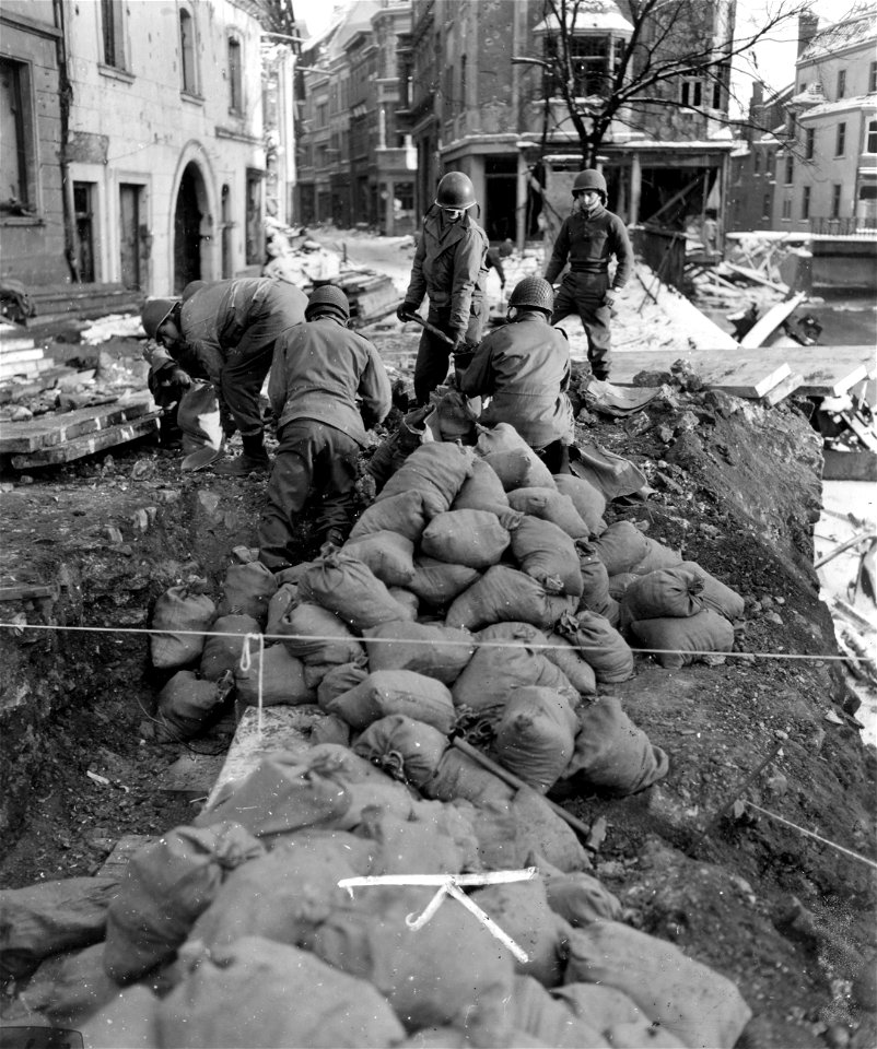 SC 405145 - Sand bags to fill abutment for bridge in Eschweiler are filled on shore before being moved into stream by engineers. 26 January, 1945.