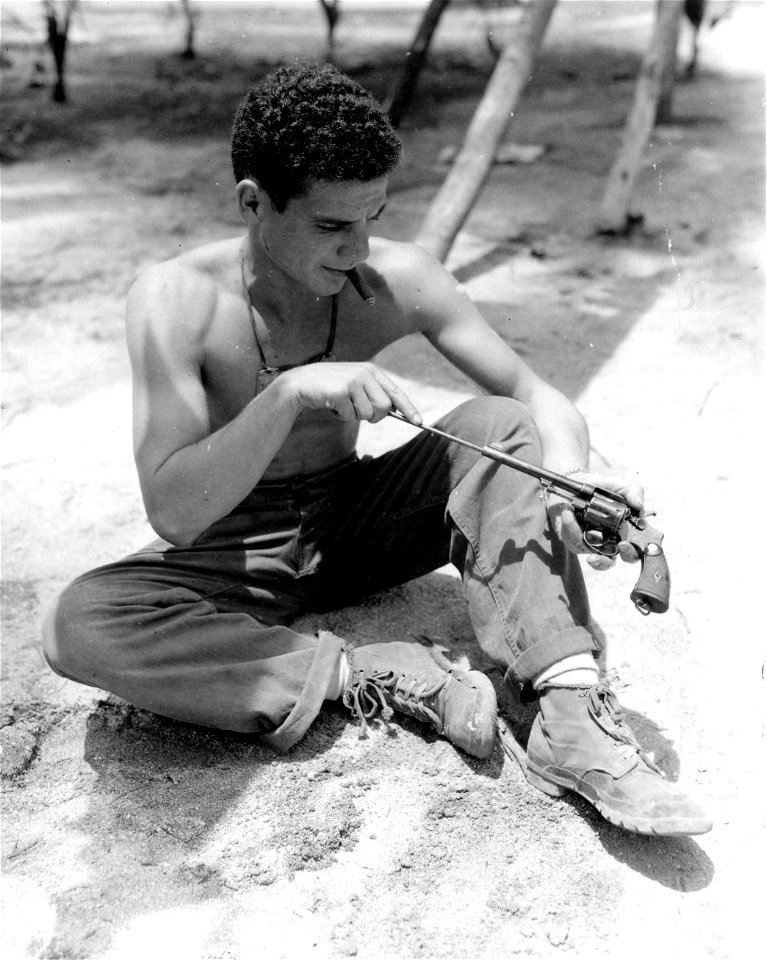 SC 364500 - Pvt. Harry Jacobs of New York City, N.Y., HDQ Troop, 1st Cavalry, makes final and cleaning of his personal revolver before invasion.