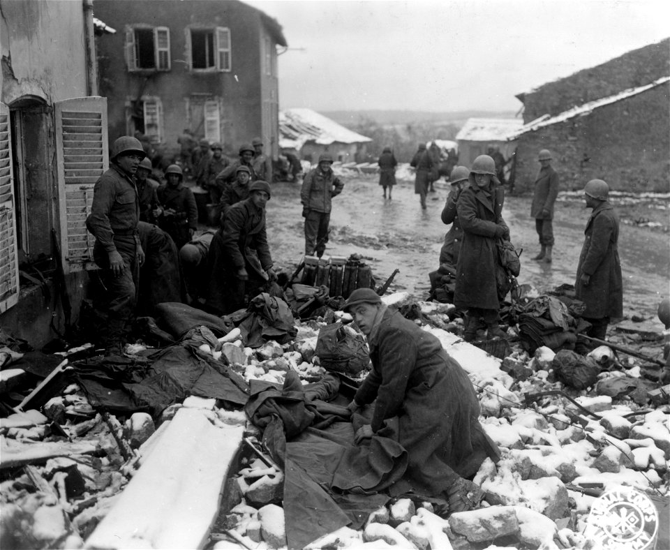 SC 374762 - American infantrymen roll equipment into light combat packs in snow-covered French village somewhere in France in preparation for entry into front-line positions.