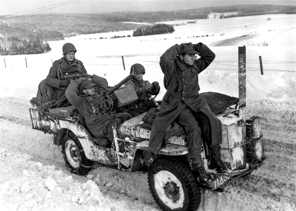 SC 198845 - Sgt. Clarence Pfeifer, Jordan, Montana, (with machine gun) and Pfc. Sherman Maness, Searcy, Ark., (driver) bring in two German prisoners captured near Longchamps, Belgium. 15 January, 1945.