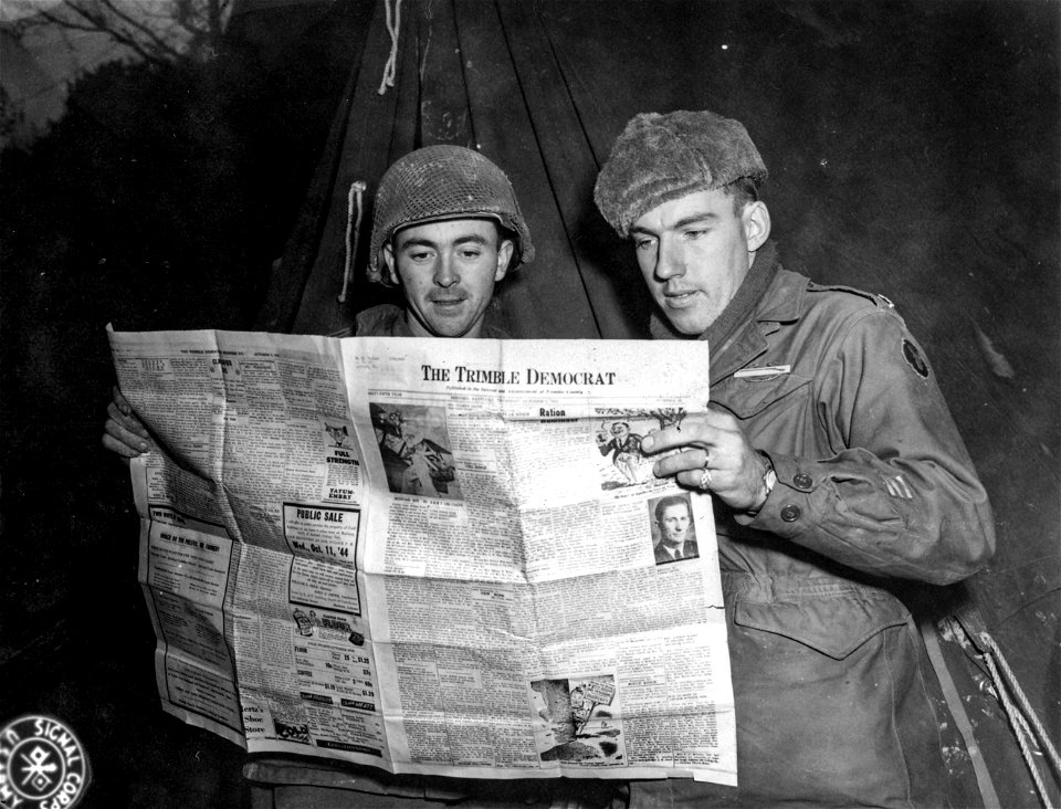 SC 396914 - 2nd Lt. Charles Pettit, of Bardstown, Kentucky, left, and Lt. Col. Benjamin J. Butler of Milton, Kentucky, read a copy of the Trimble County Democrat. 15 January, 1945.