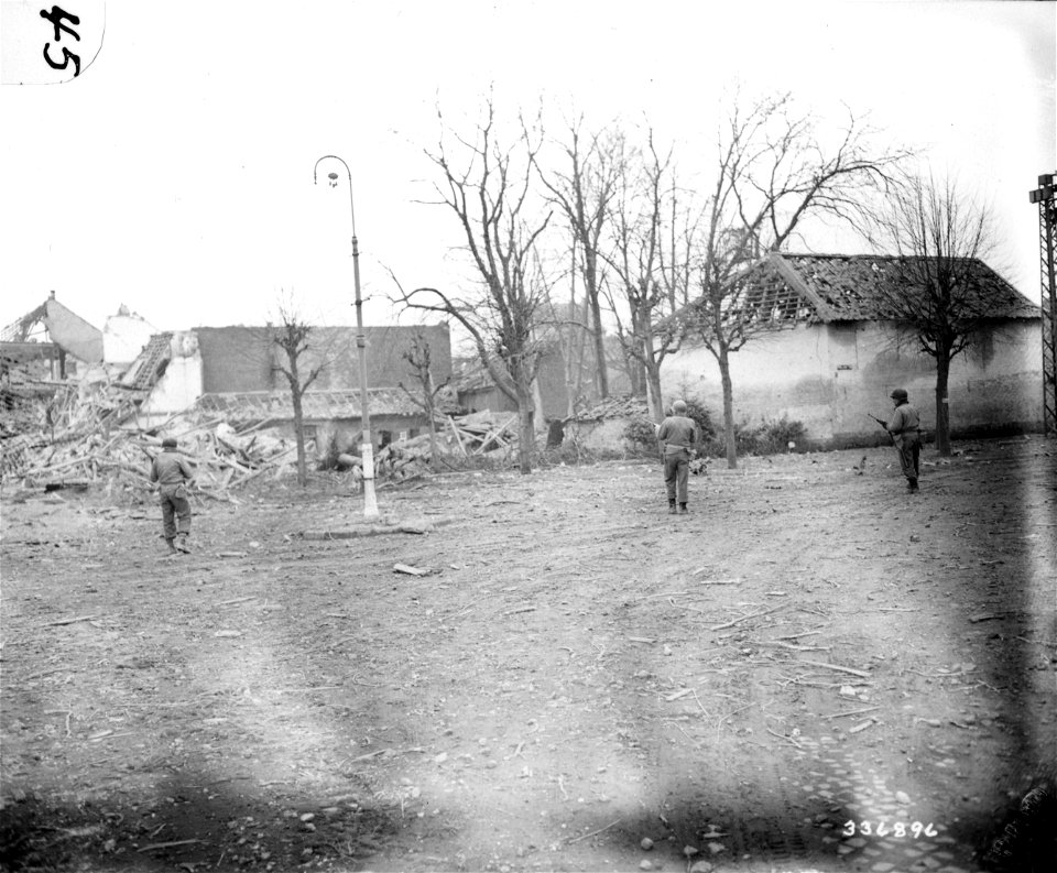 SC 336896 - Infantrymen of the 5th Armored Division of the U.S. Ninth Army advance through the wrecked town of Wickrath, Germany.
