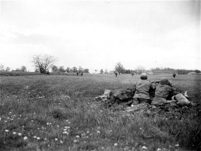 SC 270649 - Infantrymen move across open field toward burning town, one of the little strong points on road to Munich, softened up for the infantrymen by mortar fire, while in the foreground are other infantrymen covering the advancing elements. photo