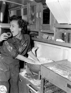 SC 195539 - Betty Jane Thomas, Seattle, Wash., a Red Cross worker somewhere in France, samples one of her own doughnuts while busily engaged in making more for soldiers. 1 October, 1944. photo