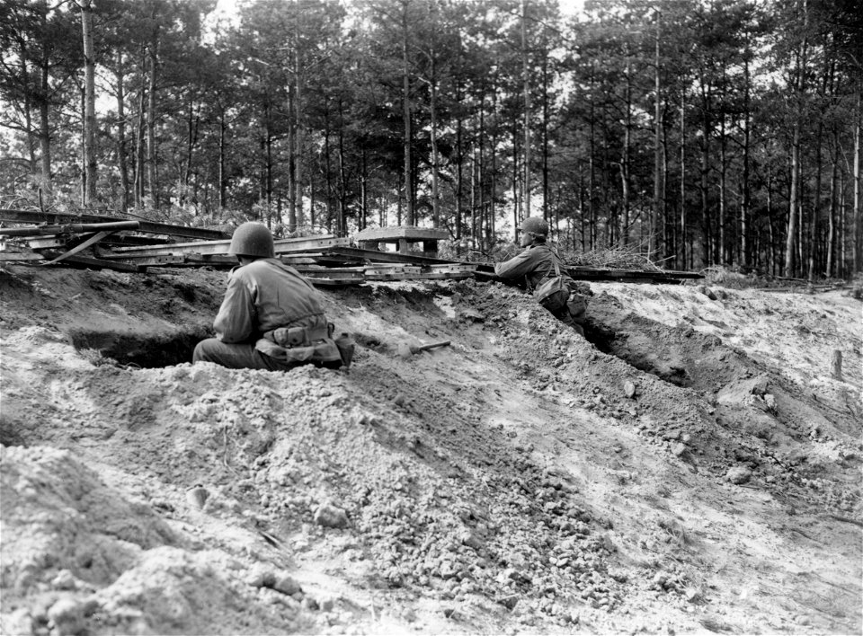 SC 270645 - A concentration of machine gun, artillery air bursts and mortar fire forces these Yank infantrymen to dig in behind a railroad bank as they are temporarily halted.