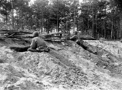 SC 270645 - A concentration of machine gun, artillery air bursts and mortar fire forces these Yank infantrymen to dig in behind a railroad bank as they are temporarily halted. photo