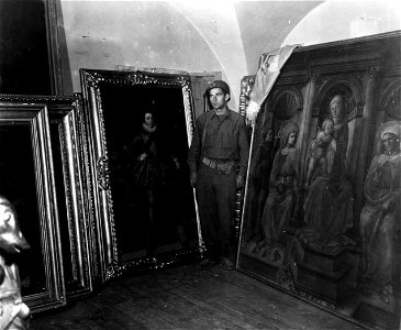 SC 374649 - Pfc. Louis A. Cilibinli, 337th F.A. Bn., 88th Div., stands guard in one of the rooms used to store several million dollars worth of art treasures stolen by the Nazis and found by men of the 88th Div. photo