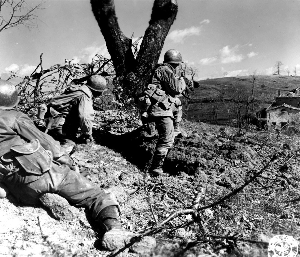 SC 270848 - Three members of Co. "K", 87th Mtn. Inf., 10th Mtn. Div., cover house in background while prisoners remove wounded Germans from house where they had refused to surrender until an assault platoon surrounded them.