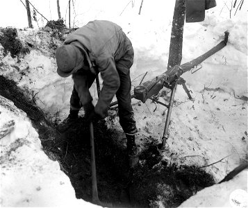 SC 364478 - Pvt. Sam Zimmerman, Goose Creek, Texas, S.V. Bat., 12th F.A. digging emplacement in 2' of snow along road to halt infantry - .50 caliber air-cooled Browning machine gun - four men can make emplacement in one hour.