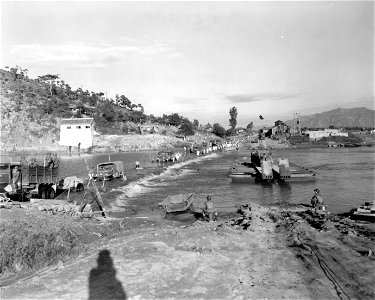 SC 348667 - Heavy trucks of the 21st Inf. Regt., 24th Inf. Div. cross the Geumho River on an underwater crossing, consisting of rocks and sandbags reinforcing the riverbed, as lighter vehicles use a ferry, during the 24th Inf. Div. advance...