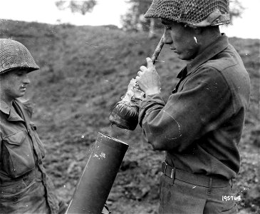 SC 195763 - Pvt. Andrew Wilder, Harlan County, Ky., cleans the mortar cylinder of a captured German 120mm mortar, now being used by the Yanks, with a makeshift rod. 29 October, 1944. photo