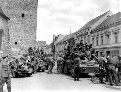 SC 335552 - American soldiers clamber over armored car of 125th Cavalry Reconnaissance Squadron of U.S. Ninth Army after their liberation from camp near Luckenwalde, Germany. photo