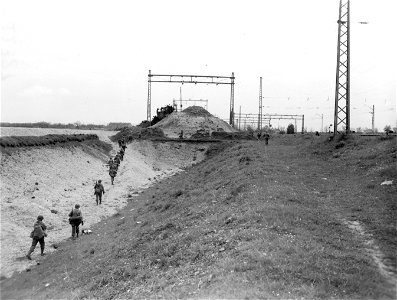 SC 270655 - Infantrymen file along the electric railway line as they enter the outskirts of Munich, Germany. 30 April, 1945. photo