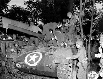 SC 195533 - Miss Betty Brittian, Pasadena, Calif., hands Cpl. Wm. B. Brooks, Clayton, Ga., inside the tank, a cup of coffee and doughnuts. 1 October, 1944.