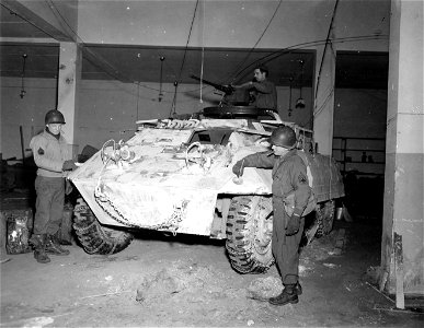 SC 374718 - S/Sgt. G. B. Hennenmen, Du Bois, Pa., Tec 5 A. R. Sears, Houston, MD, and T/Sgt. J. C. Esry, Abbeville, Ala., all of the 95th Division, working on a snow camouflage job for their M-8 armoured scout car. photo