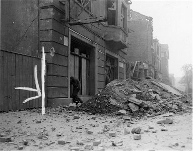 SC 335306 - Two Yank infantrymen cover their heads and hug the walls of destroyed building in bitterly-contested Heilbronn, as they hear the warning scream of a German Nebelwerfers coming in dangerously close.