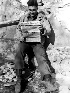 2nd Lt. Richard E. Smith, 55 Mill St., Athens, Ohio, reads the Athens Messenger during a lull in the fighting on the Fifth Army front in Italy. photo