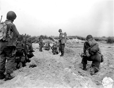 SC 270615 - Troops of the 15th Inf. Regt., 3rd Div., take cover in the sand as they await orders to advance inland. 15 August, 1944.