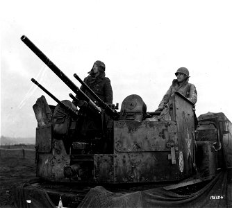 SC 196124 - Bundled up in overcoats against wintry blasts in France, two soldiers mount guard on their anti-aircraft gun mount.