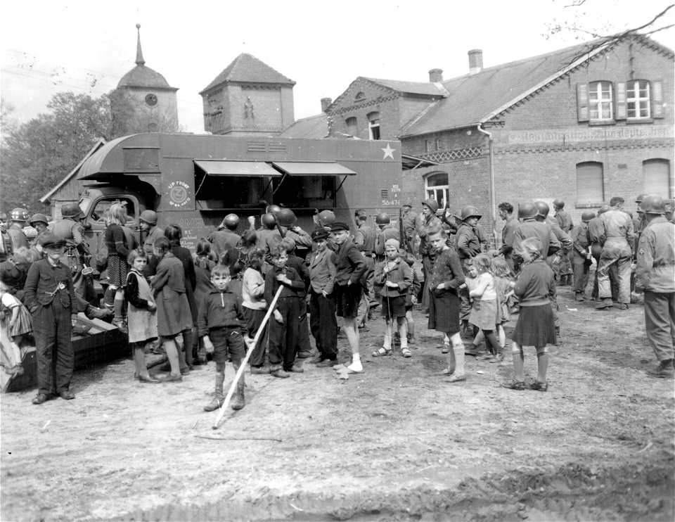 SC 329795 - German civilians stand around as men of the 35th Division, 9th U.S. Army, line up for coffee and doughnuts at Sandbeindorf, Germany. 24 April, 1945.