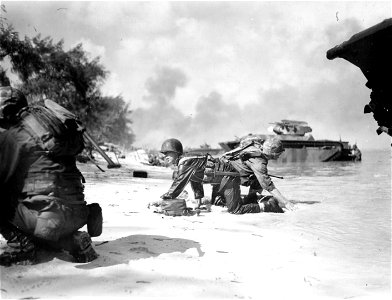 Swing Shift? It appears that one Marine is relieving another on the beach at Saipan but they are really crawling, under enemy fire, to their assigned positions. photo