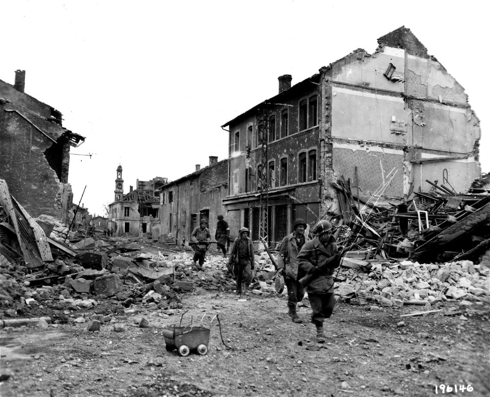 SC 196146 - A squad of infantrymen patrol through the streets of the shattered town of Maizieres-les-Metz, France, on the hunt for any remaining enemy snipers.