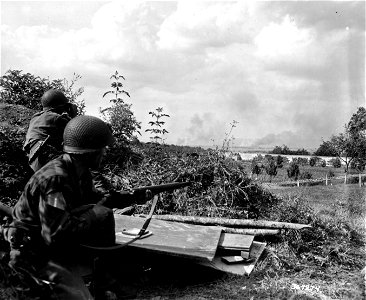 SC 364274 - Pvt. Herbert Knowles, Toledo, Wash., and Pvt. Charles Brown, Richmond, Ind., peer over the top of a knoll to view the burning German convoy in the distance, blasted by air and artillery near Chambois.