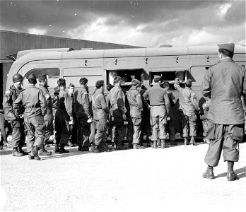 SC 195701 - Members of an American airborne unit flock to an American Red Cross Clubmobile for coffee and donuts on the eve of their takeoff for the airborne invasion of Holland. 16 September, 1944.
