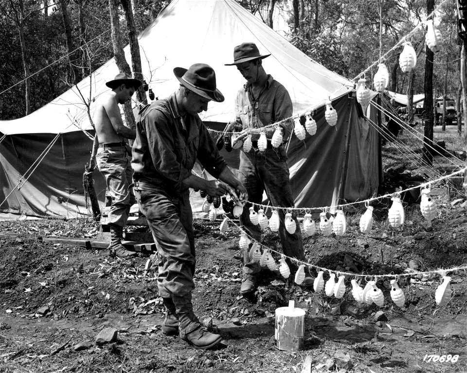 SC 170698 - Pvt. Floyd West, Pfc. Charles R. Cooper, and Pvt. Alex Williams are shown painting hand grenades. Australia. 27 October, 1942. photo
