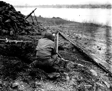 SC 364330 - A First U.S. Army machine gunner shoots a stream of lead into floating objects on the Rhine River, to explode mines being floated down the river by the Germans in an effort to knock out bridges used by the Americans... photo