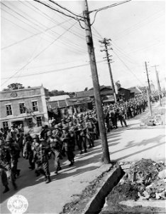 SC 270791 - Troops of the 17th Inf., 7th Div., marching through streets of Jansin with civilians watching. Korea. 9 September, 1945. photo
