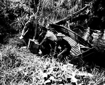 SC 170689 - Men unloading foodstuffs from row boat preparatory to carrying it thru jungle path, somewhere in New Guinea. November 13, 1942. photo